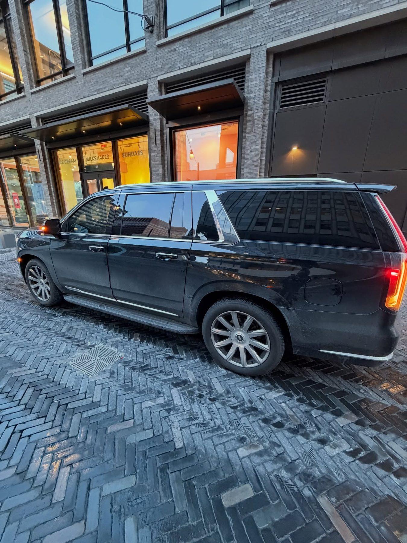 Black executive SUV on a city street at night by a lit storefront